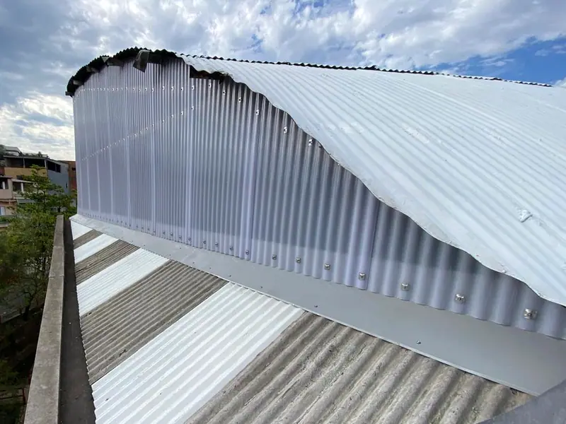 O fechamento do alto do telhado depois da obra, com as telhas novas, sob o céu azul