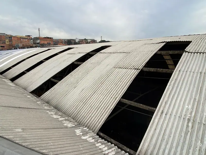 Telhados em arco durante a obra, com faixas de telhas retiradas e os vãos abertos