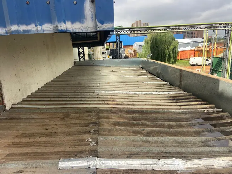 Um telhado metálico antes da obra, com as telhas antigas gastas e remendadas